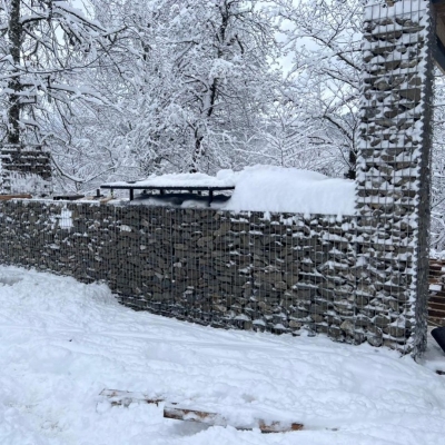 Снежный пейзаж с габионной мангальной зоной на фоне зимнего леса