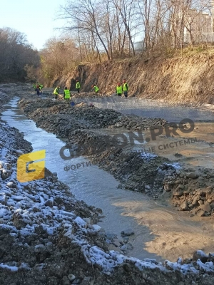 Рабочие укладывают камень в габионные конструкции на правом берегу реки Кудепста